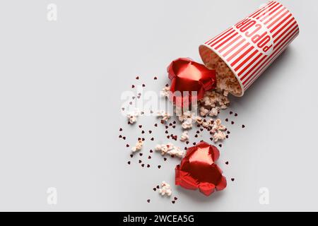 Secchio di popcorn con palloncini a forma di cuore e coriandoli su sfondo bianco. Festa di San Valentino Foto Stock