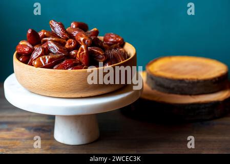 frutta secca di datteri in una pentola di legno sul supporto per torta bianca Foto Stock