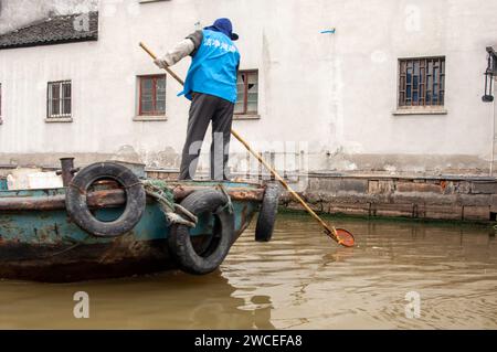 Uomo che raccoglie spazzatura dai canali di Shanghai in Cina Foto Stock