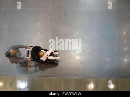 Vista dall'alto di una donna che spinge un bambino in un passeggino - novembre 2023 Foto Stock