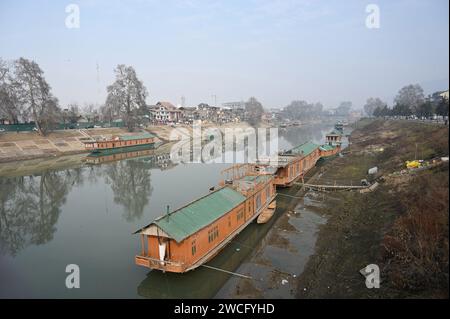 Srinagar, India. 15 gennaio 2024. SRINAGAR, INDIA - 15 GENNAIO: Le case galleggianti sono viste sulle rive del fiume Jhelum il 15 gennaio 2024 a Srinagar, India. Il livello dell'acqua in Jhelum raggiunge il livello più basso con l'incantesimo dell'asciutto che continua. (Foto di Waseem Andrabi/Hindustan Times/Sipa USA) credito: SIPA USA/Alamy Live News Foto Stock