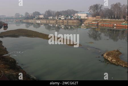 Srinagar Kashmir, India. 15 gennaio 2024. Vista di una porzione secca del fiume Jhelum a Srinagar. Un lungo periodo invernale secco lascia il fiume Jhelum a Historic Low, mettendo a rischio le case galleggianti e deludenti sciatori a Gulmarg. Il 15 gennaio 2024, Srinagar Kashmir, India. (Immagine di credito: © Firdous Nazir/eyepix via ZUMA Press Wire) SOLO USO EDITORIALE! Non per USO commerciale! Foto Stock