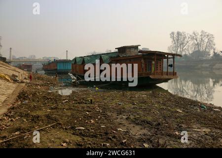 Srinagar, India. 15 gennaio 2024. 15 gennaio 2024, Srinagar Kashmir, India: Veduta di una porzione secca del fiume Jhelum a Srinagar. Un lungo periodo invernale secco lascia il fiume Jhelum a Historic Low, mettendo a rischio le case galleggianti e deludenti sciatori a Gulmarg. Il 15 gennaio 2024, Srinagar Kashmir, India. (Foto di Firdous Nazir/Eyepix Group) credito: SIPA USA/Alamy Live News Foto Stock