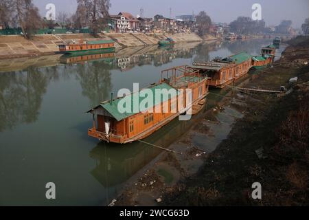 Srinagar, India. 15 gennaio 2024. 15 gennaio 2024, Srinagar Kashmir, India: Le case galleggianti sono viste sulle rive del fiume Jhelum a Srinagar. Un lungo periodo invernale secco lascia il fiume Jhelum a Historic Low, mettendo a rischio le case galleggianti e deludenti sciatori a Gulmarg. Il 15 gennaio 2024, Srinagar Kashmir, India. (Foto di Firdous Nazir/Eyepix Group) credito: SIPA USA/Alamy Live News Foto Stock