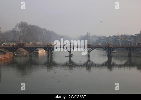 Srinagar, India. 15 gennaio 2024. 15 gennaio 2024, Srinagar Kashmir, India: I pendolari attraversano un ponte sul fiume Jhelum a Srinagar . Un lungo periodo invernale secco lascia il fiume Jhelum a Historic Low, mettendo a rischio le case galleggianti e deludenti sciatori a Gulmarg. Il 15 gennaio 2024, Srinagar Kashmir, India. (Foto di Firdous Nazir/Eyepix Group) credito: SIPA USA/Alamy Live News Foto Stock