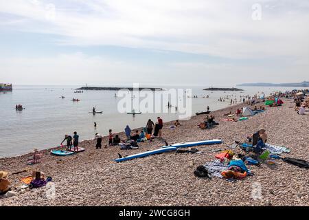 Spiaggia di Sidmouth nel Devon, 2023, calda giornata autunnale e le persone si rilassano e nuotano sulla spiaggia di ciottoli di pietra, sulla costa di Sidmouth, Inghilterra, Regno Unito Foto Stock