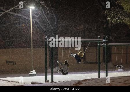 Silver Spring, Maryland, USA. 16 gennaio 2024. Due ragazze giocano e realizzano video selfie sugli altalene al Pine Crest Park mentre la neve cade lunedì 15 gennaio 2024 a Silver Spring, Maryland. L'area era sotto un allarme di tempesta invernale, con un accumulo totale di neve di 4-6 cm previsto per la mattina seguente. (Immagine di credito: © Eric Kayne/ZUMA Press Wire) SOLO USO EDITORIALE! Non per USO commerciale! Foto Stock