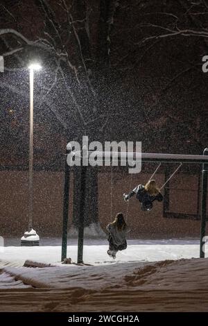 Silver Spring, Maryland, USA. 16 gennaio 2024. Due ragazze giocano sulle altalene al Pine Crest Park mentre la neve cade lunedì 15 gennaio 2024 a Silver Spring, Maryland. L'area era sotto un allarme di tempesta invernale, con un accumulo totale di neve di 4-6 cm previsto per la mattina seguente. (Immagine di credito: © Eric Kayne/ZUMA Press Wire) SOLO USO EDITORIALE! Non per USO commerciale! Foto Stock