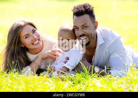 Genitori multietnici e bambini di razza mista nel parco. Ritratto multirazziale all'aperto per tutta la famiglia. Bambino birazziale in giardino. Famiglia eterogenea. afroamericana Foto Stock