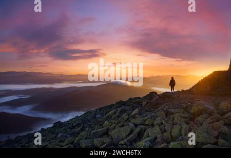 Silhouette di una ragazza sulla cima di una montagna al mattino all'alba. Splendido paesaggio naturale di una donna di successo sulla cima della montagna, cielo spettacolare a d Foto Stock