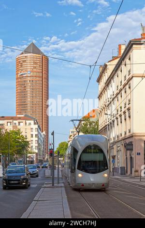 Lione, Francia - 10 giugno 2018: Tram che circola per le strade della capitale della regione Auvergne-Rhône-Alpes con dietro, la Torre Part-Dieu. Foto Stock