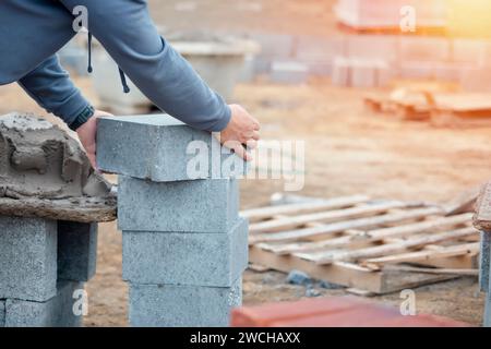 Muratore che posa blocchi di calcestruzzo ad alta densità Foto Stock