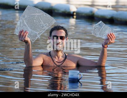 Londra, Regno Unito. 16 gennaio 2024. Un membro del Serpentine Swimming Club riposa una tazza di tè sul ghiaccio, mentre rompe pezzi di ghiaccio che hanno coperto il Serpentine Lake nel centro di Londra, seguendo temperature sotto zero durante la notte. Questa settimana il Met Office ha emesso avvisi meteorologici gialli di ghiaccio e neve per gran parte del Regno Unito, con temperature che dovrebbero scendere a -10 gradi celsius in alcune parti. Crediti fotografici: Ben Cawthra/Sipa USA credito: SIPA USA/Alamy Live News Foto Stock