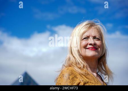 donna in pensione sorridente con capelli biondi e cielo blu sullo sfondo Foto Stock