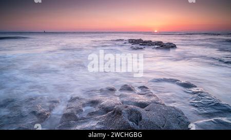 Costa rocciosa a Nash Point, Glamorgan, Galles meridionale. Tramonto sulla costa, lunga esposizione per attenuare i movimenti in mare. Foto Stock