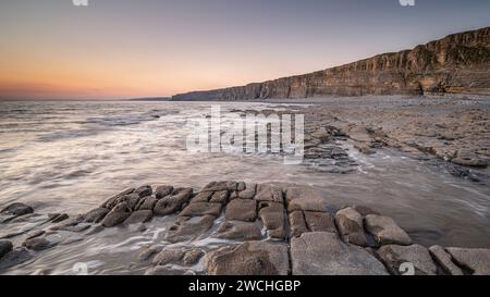 Costa rocciosa a Nash Point, Glamorgan, Galles meridionale. Tramonto sulla costa, lunga esposizione per attenuare i movimenti in mare. Foto Stock