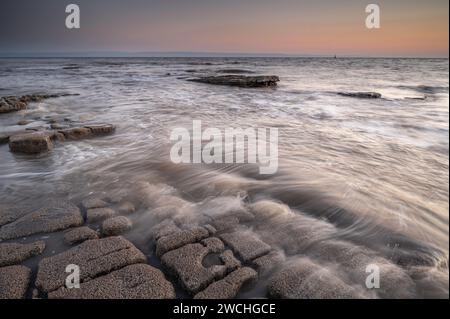 Costa rocciosa a Nash Point, Glamorgan, Galles meridionale. Tramonto sulla costa, lunga esposizione per attenuare i movimenti in mare. Foto Stock