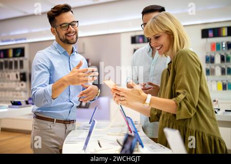 Il consulente di vendita consiglia le persone che scelgono nuovi dispositivi digitali nei punti vendita. Consulenza professionale Foto Stock