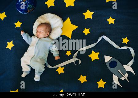 bambino bambino astronauta addormentato su uno sfondo del cielo con la nave spaziale Foto Stock