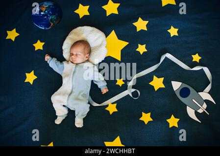 bambino bambino astronauta addormentato su uno sfondo del cielo con la nave spaziale Foto Stock