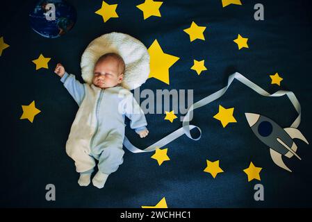 bambino bambino astronauta addormentato su uno sfondo del cielo con la nave spaziale Foto Stock