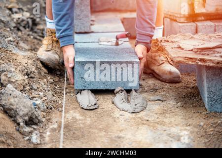 Muratore che posa blocchi di calcestruzzo ad alta densità Foto Stock