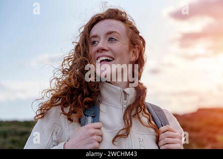 Allegra e felice viaggiatrice con una giacca bianca e uno zaino che viaggia in montagna nel Peak District. Concetto di stile di vita turistico locale Foto Stock