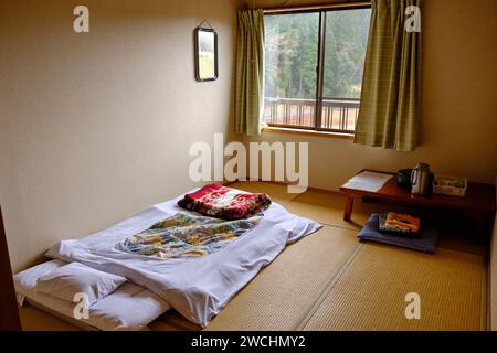 Camera da letto in un tipico Minshuku, un bed and breakfast a gestione familiare in stile giapponese, con biancheria da letto e piccolo tavolo con il necessario per preparare il te' Foto Stock