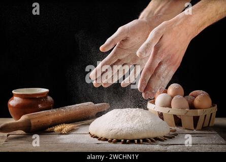 L'uomo prepara l'impasto del pane su un tavolo da cucina in legno. Fare pane fatto in casa. Foto Stock