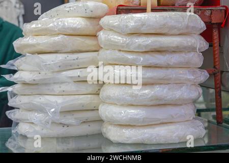 Blocco impilato di prodotti caseari a base di formaggio bianco presso il mercato agricolo Foto Stock