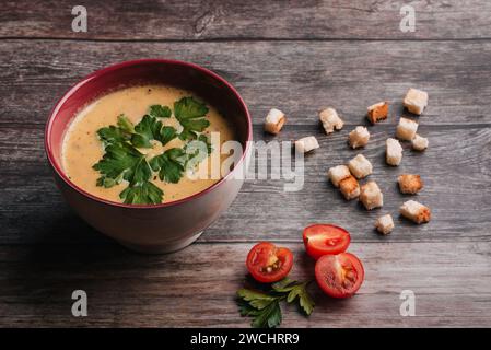 Zuppa di crema di zucca in una ciotola con prezzemolo su un tavolo di legno con cracker e pomodori. Cibo tradizionale autunnale vegetariano dieta per Halloween Foto Stock