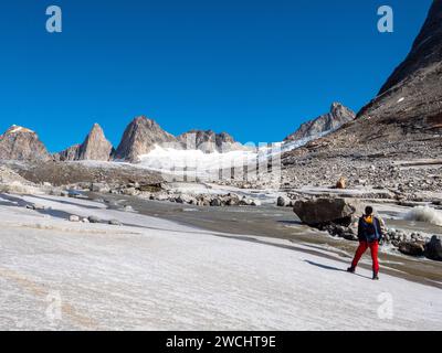 Un alpinista si erge su una lastra di roccia e si affaccia sulla catena montuosa Niialigaq in Groenlandia Foto Stock