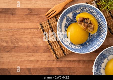 Panino di patate dolci fatto in casa con carne di maiale macinata, funghi e farciture di bambù tritate all'interno in una ciotola su fondo di legno. Foto Stock