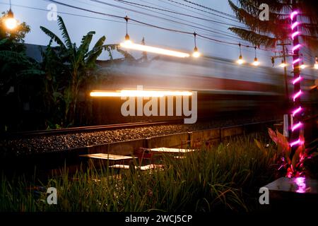 Il treno passeggeri si muove velocemente al tramonto. Foto Stock