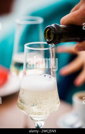 Primo piano di champagne versato da una bottiglia in un bicchiere di champagne. Foto Stock