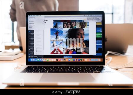 Parigi, Francia - 28 ottobre 2022: Un computer portatile Apple macbook Pro che mostra un'applicazione di fotoritocco con varie immagini di una persona è situato su una scrivania molto occupata, a dimostrazione di un processo di editing professionale in corso. Foto Stock