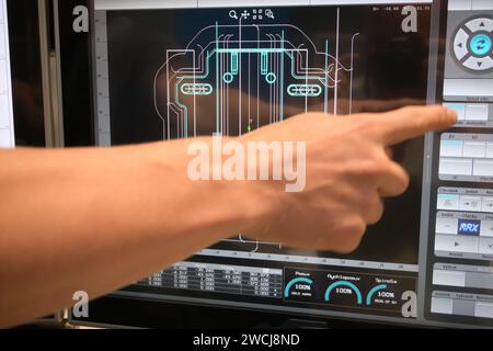 monitor cnc durante la visualizzazione del programma, il lavoratore punta con la mano. Foto Stock