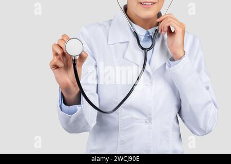 Allegro medico millenario caucasico in camice bianco, ascolta respirare con stetoscopio, tagliato Foto Stock