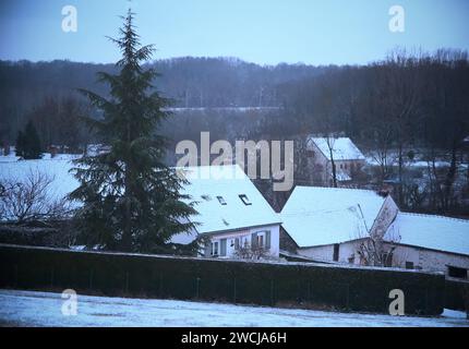 Cortile coperto di neve con alberi che circondano una vecchia casa a Saint-Loup-de-Naud Foto Stock