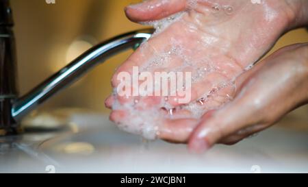 la donna si lava le mani sotto l'acqua corrente, usa il sapone. Foto Stock