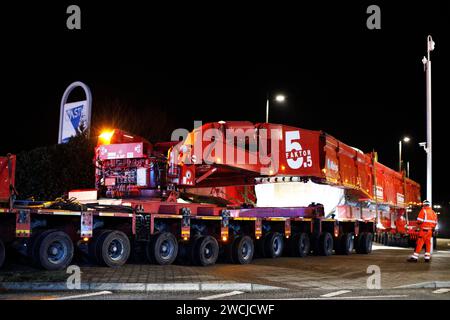 Merthyr Tydfil, Galles del Sud, Regno Unito. 15 gennaio 2024. Un carico anomalo dell'HGV ha attraversato il centro della città lunedì sera, dopo non essere stato in grado di completare il viaggio a Hirwaun ieri sera a causa del maltempo. Il gigantesco camion di 78 metri era scortato dalla polizia e le strade chiuse per consentire il passaggio del camion, che attirava una grande folla che lo osservava passare. Crediti: Andrew Bartlett/Alamy Live News Foto Stock