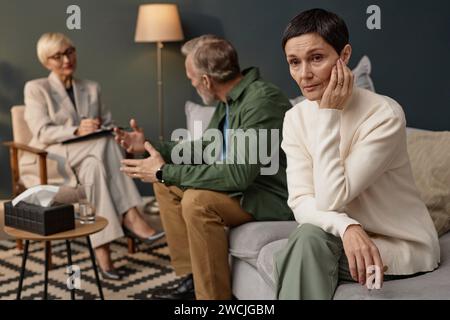 Ritratto di donna matura in difficoltà che guarda lontano durante la sessione di terapia di coppia o di consulenza Foto Stock