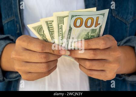 Le mani di una donna che regge banconote da 100 dollari, e' di fronte al fronte che tiene con due mani. Foto Stock