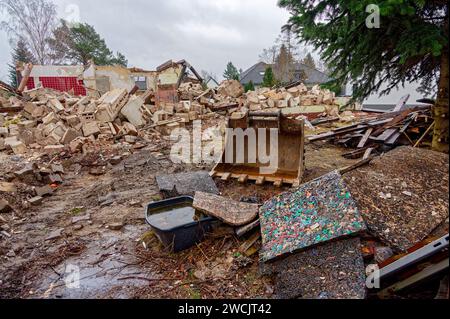 La pala di un escavatore in un cantiere in cui viene demolito un vecchio edificio residenziale. Foto Stock