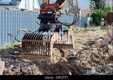 La pala di un escavatore in un cantiere in cui viene demolito un vecchio edificio residenziale. Foto Stock
