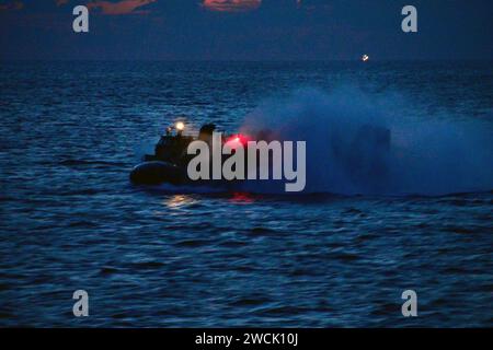 Un mezzo da atterraggio, cuscino d'aria, transita accanto alla USS Wasp durante le operazioni LCAC notturne. Foto Stock