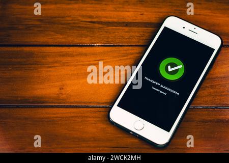 Trasferimenti di denaro. Pagamento online. Smartphone con notifica di pagamento riuscita sullo schermo su sfondo in legno Foto Stock