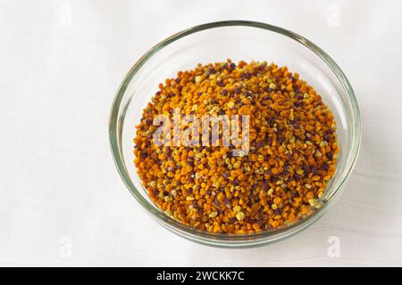 Granuli di polline d'api in una ciotola di vetro su sfondo bianco. Superfood, miscela di nettare di fiori, enzimi, miele, secrezioni di cera. Nutrienti, amminoacidi, l Foto Stock