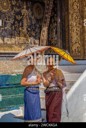 Due graziose giovani donne del sud-est asiatico in posa per una fotografia ai gradini del SIM a Wat Xieng Thong, Luang Prabang, Laos Foto Stock