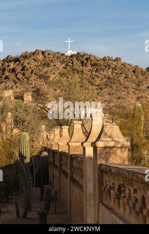 La Grotto Hill con la sua croce bianca all'esterno del muro protettivo della missione San Xavier del Bac, Tucson Arizona. Foto Stock